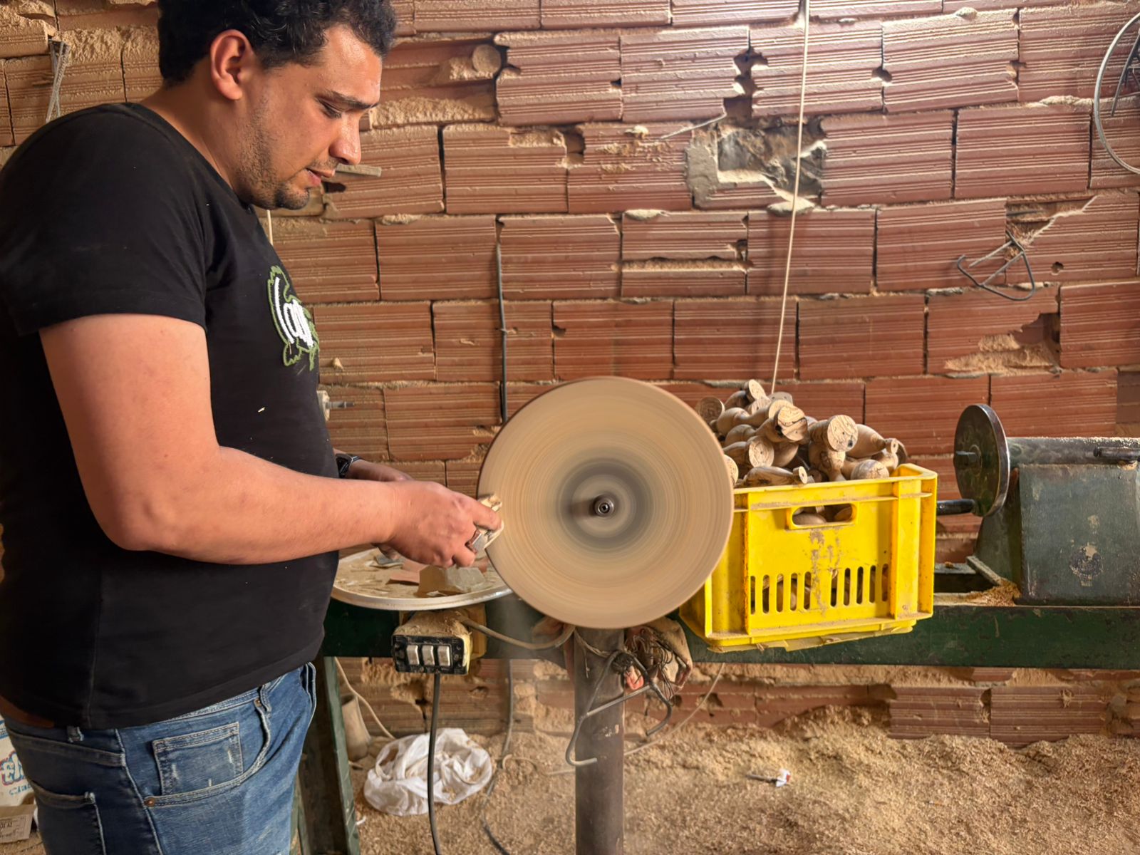 Artisan smoothing a wooden chew on a disc sander